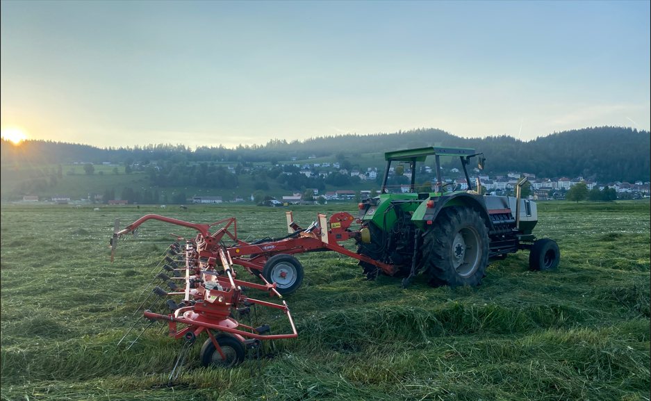Tracteur Deutz avec faneuse dans un champ des Ponts-de-Martel au coucher du soleil